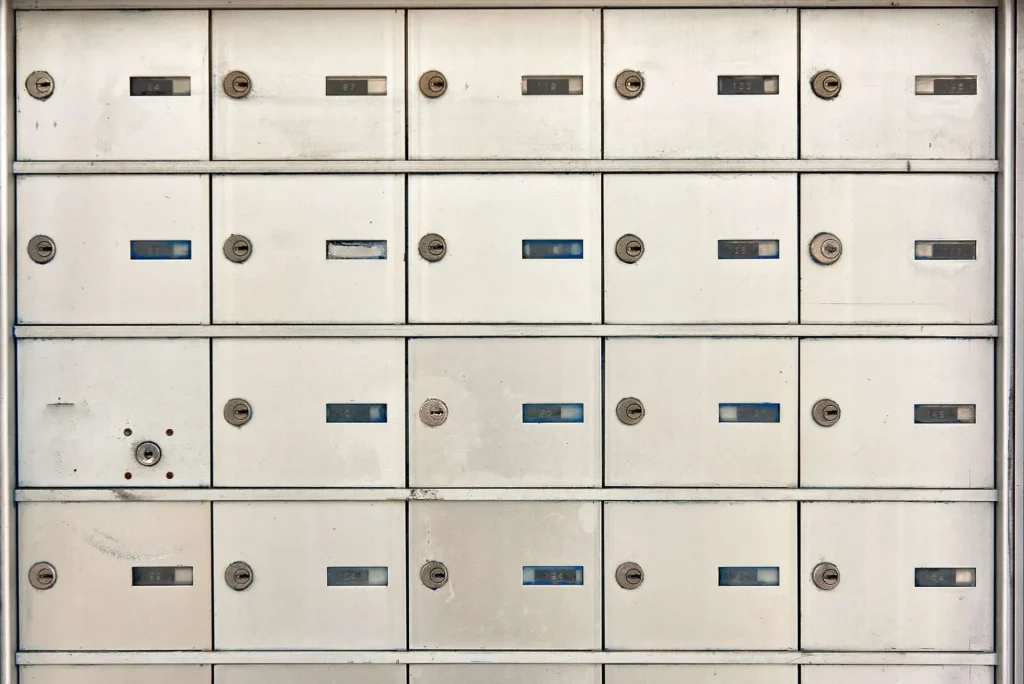A wall of white mailboxes with blue and silver numbers.