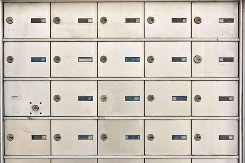 A wall of white mailboxes with blue and black numbers.